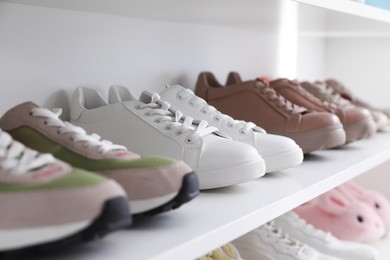 Photo of Different footwear on shelf indoors, closeup. Shoe storage