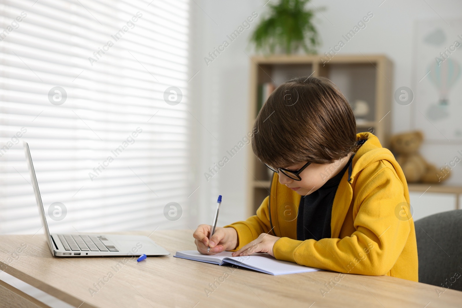 Cute little boy doing homework at table indoors Photo of Cute little boy doing homework at table indoors