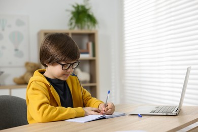 Photo of Cute little boy doing homework at table indoors
