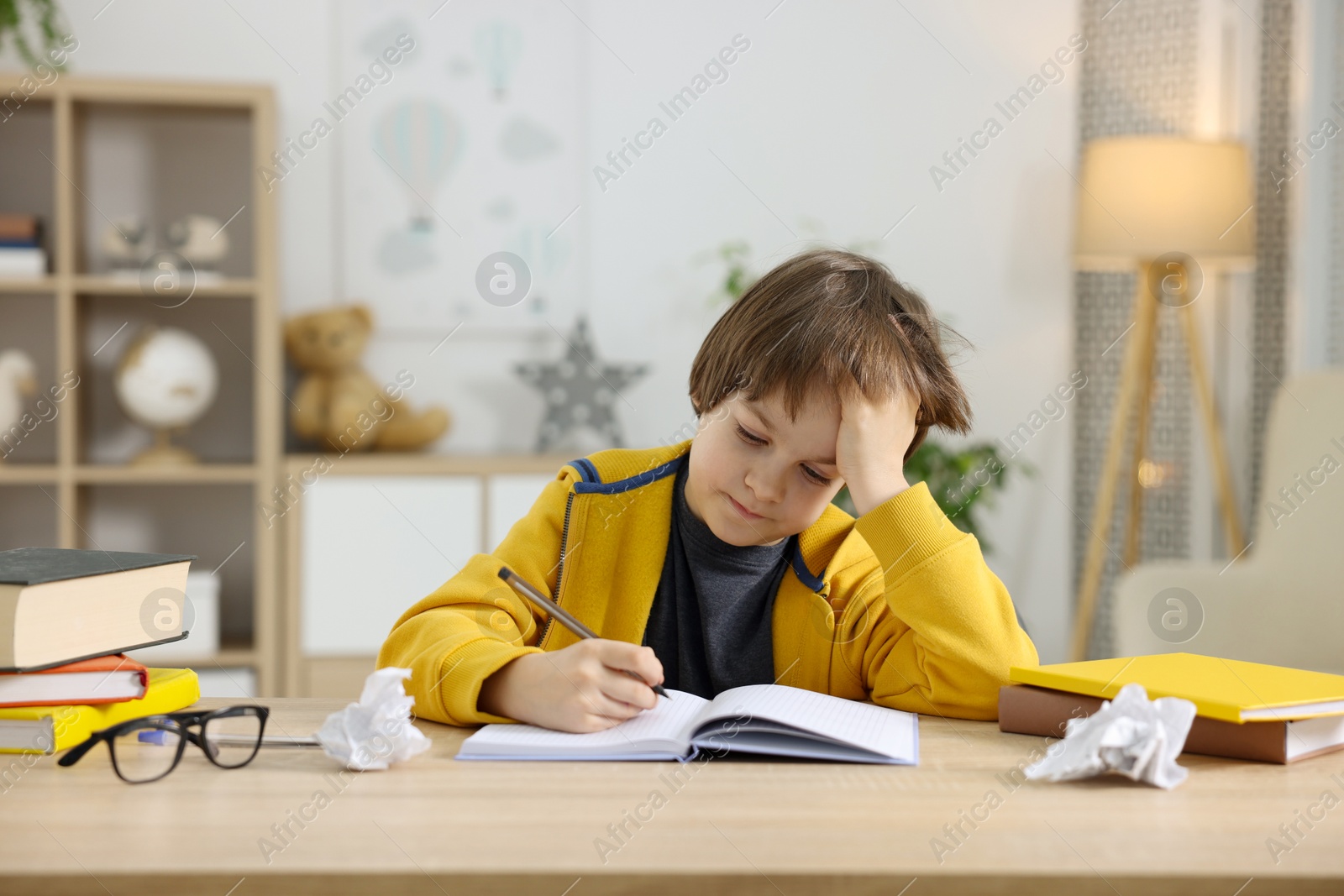 Tired little boy doing homework at table indoors Photo of Tired little boy doing homework at table indoors
