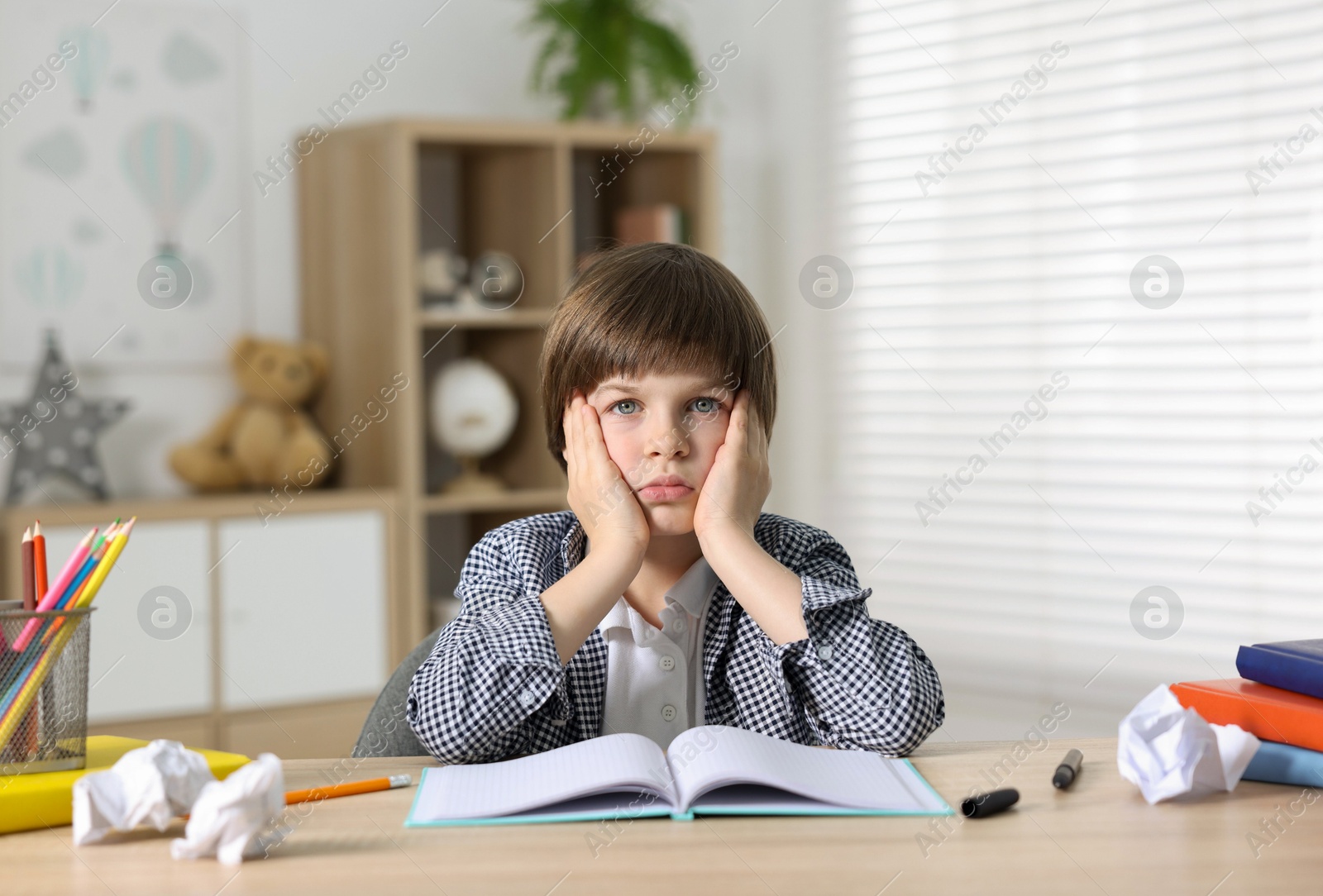 Tired little boy doing homework at table indoors Photo of Tired little boy doing homework at table indoors