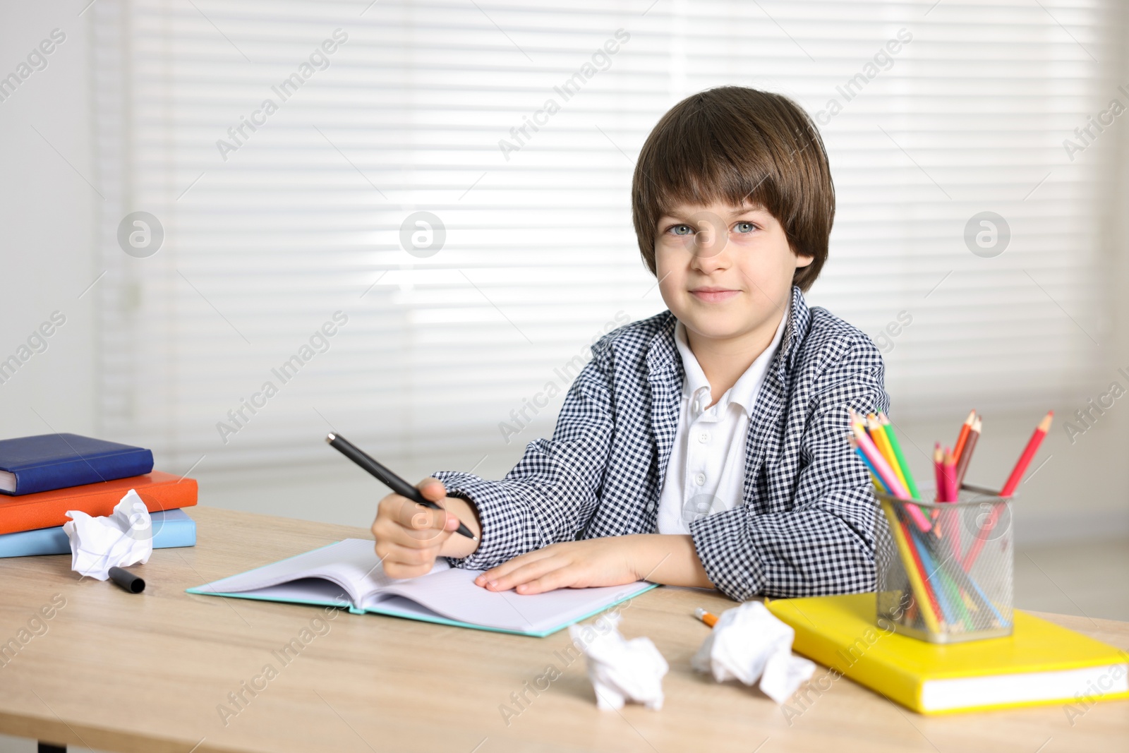 Cute little boy doing homework at table indoors Photo of Cute little boy doing homework at table indoors