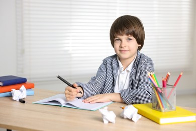 Photo of Cute little boy doing homework at table indoors