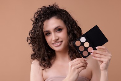 Photo of Smiling woman with eyeshadow palette on beige background