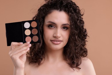 Photo of Woman with eyeshadow palette on beige background