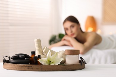 Photo of Woman relaxing in salon, focus on spa products and flower