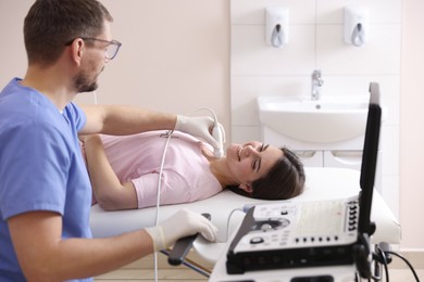 Photo of Sonographer conducting ultrasound examination of woman's thyroid gland in clinic
