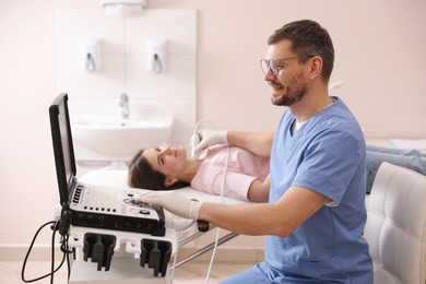 Photo of Sonographer conducting ultrasound examination of woman's thyroid gland in clinic