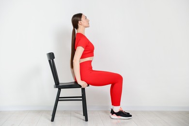 Photo of Beautiful woman exercising with chair at home