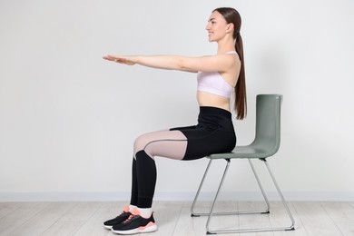 Photo of Beautiful woman stretching on chair at home