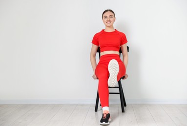 Photo of Beautiful woman stretching on chair at home, space for text