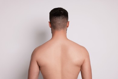 Photo of Man after scoliosis treatment on light background, back view