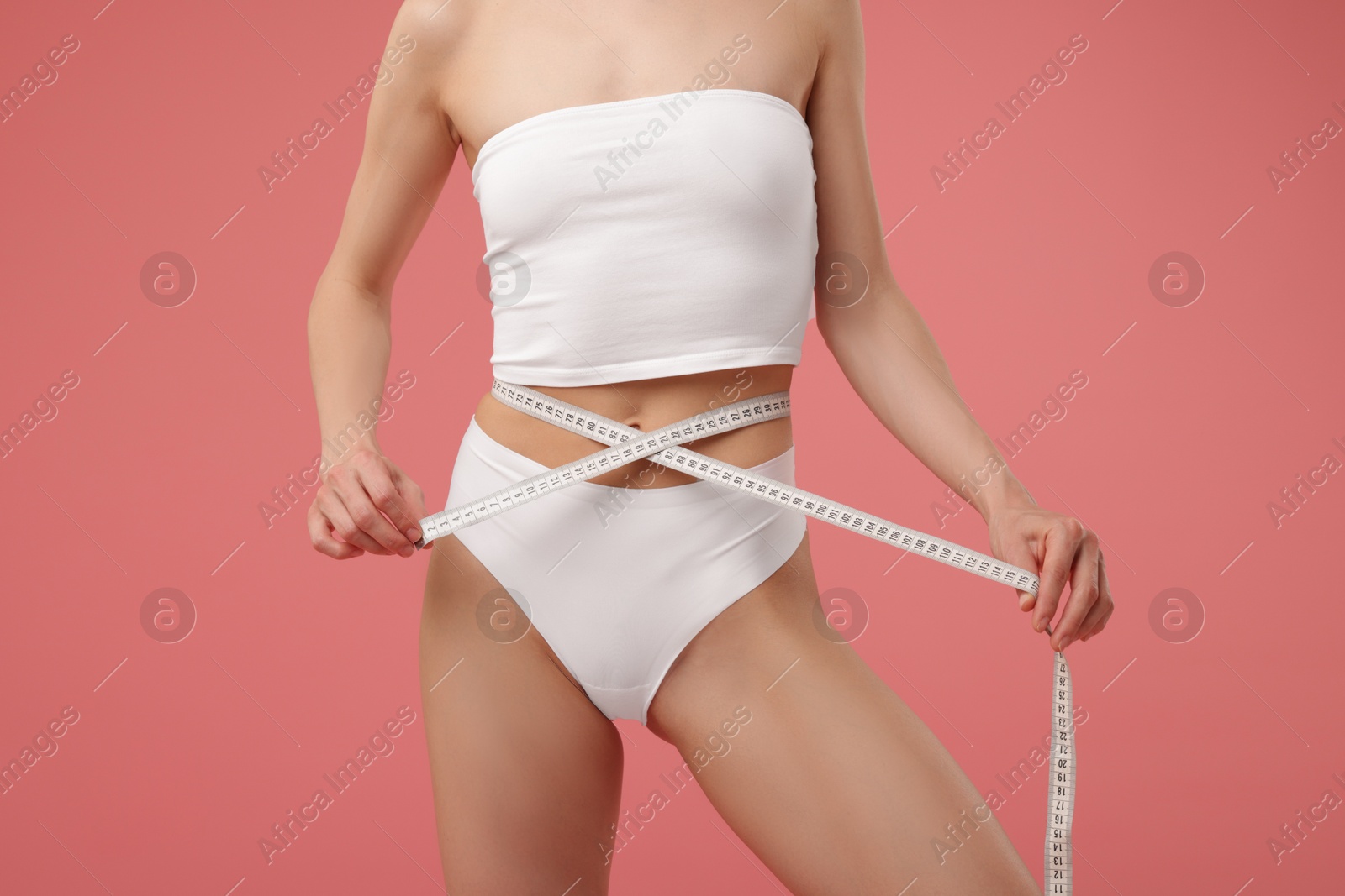 Woman with slim body and measuring tape on pink background, closeup Photo of Woman with slim body and measuring tape on pink background, closeup