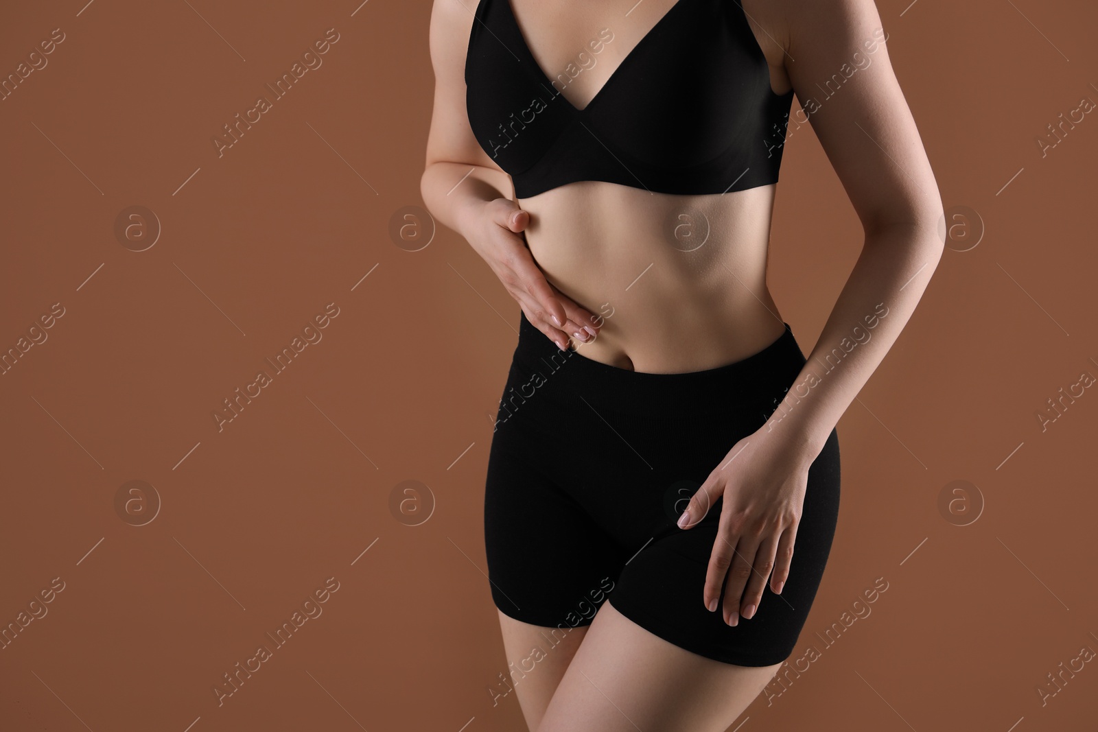 Attractive woman against brown background, closeup on belly. Space for text Photo of Attractive woman against brown background, closeup on belly. Space for text