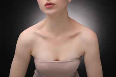 Photo of Woman with beautiful collarbones and neck on black background, closeup