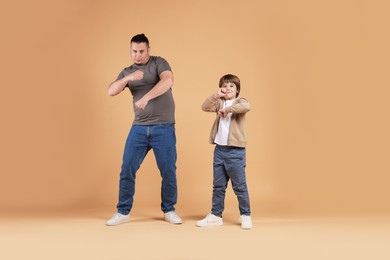 Photo of Father and his son dancing together on beige background