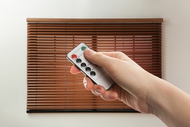 Image of Woman using remote to control blinds in room, closeup