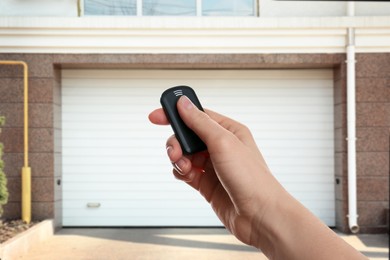 Image of Woman using remote to control garage door outdoors, closeup