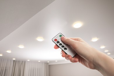 Image of Woman using remote to control lighting in room, closeup