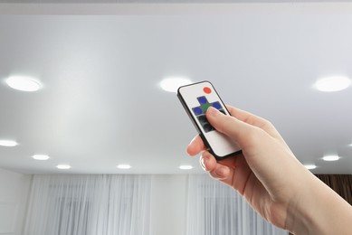 Image of Woman using remote to control lighting in room, closeup