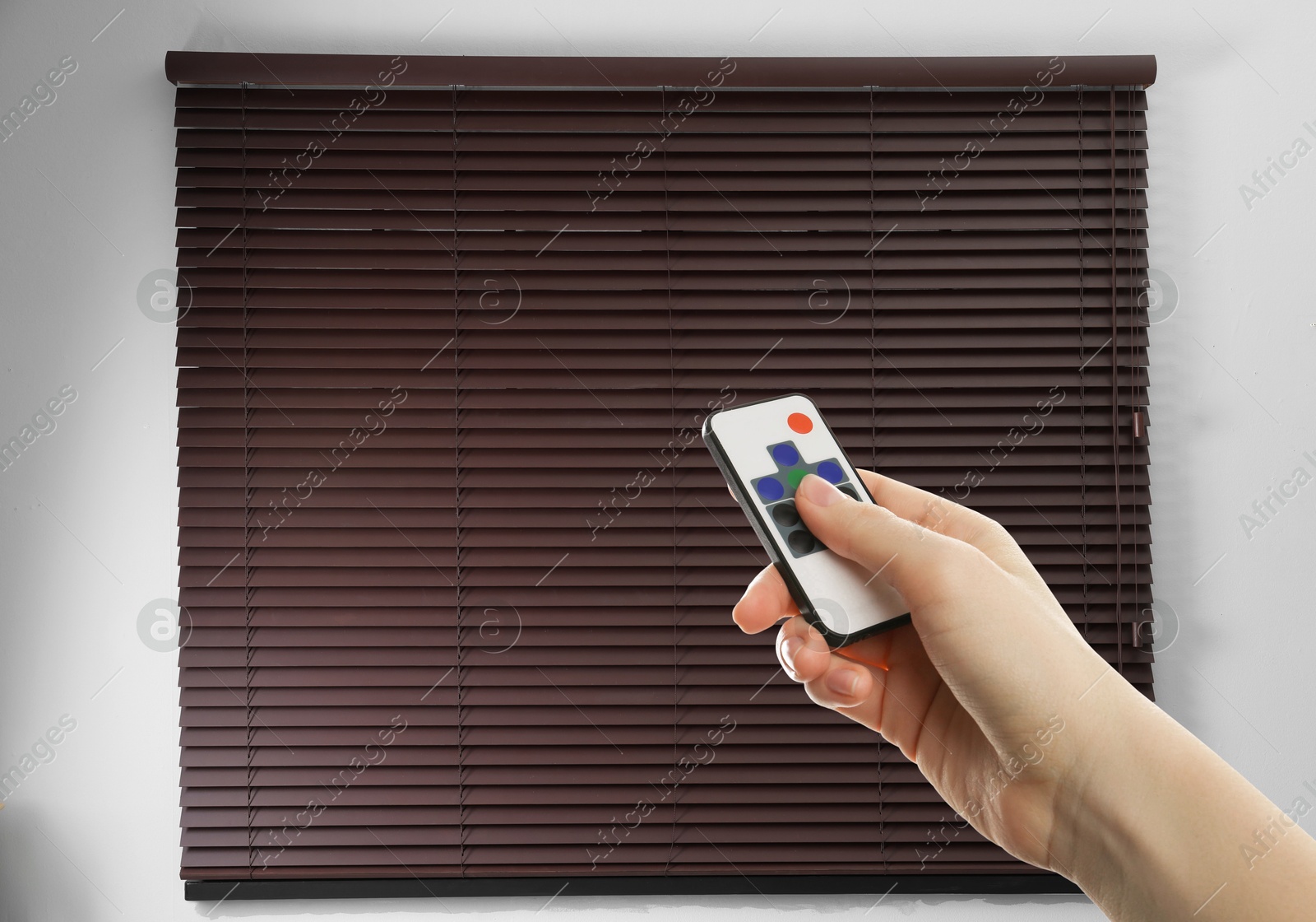 Woman using remote to control blinds in room, closeup Image of Woman using remote to control blinds in room, closeup