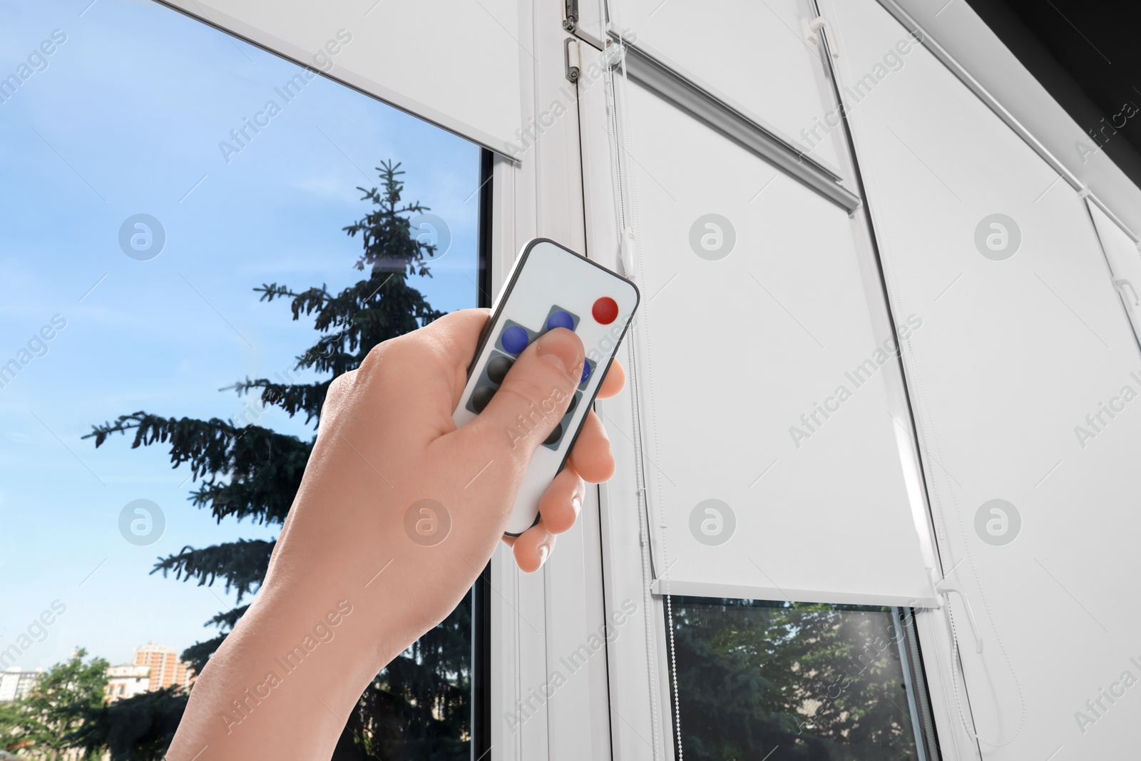 Woman using remote to control blinds in room, closeup Image of Woman using remote to control blinds in room, closeup
