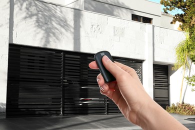Image of Woman using remote to control roller shutters outdoors, closeup