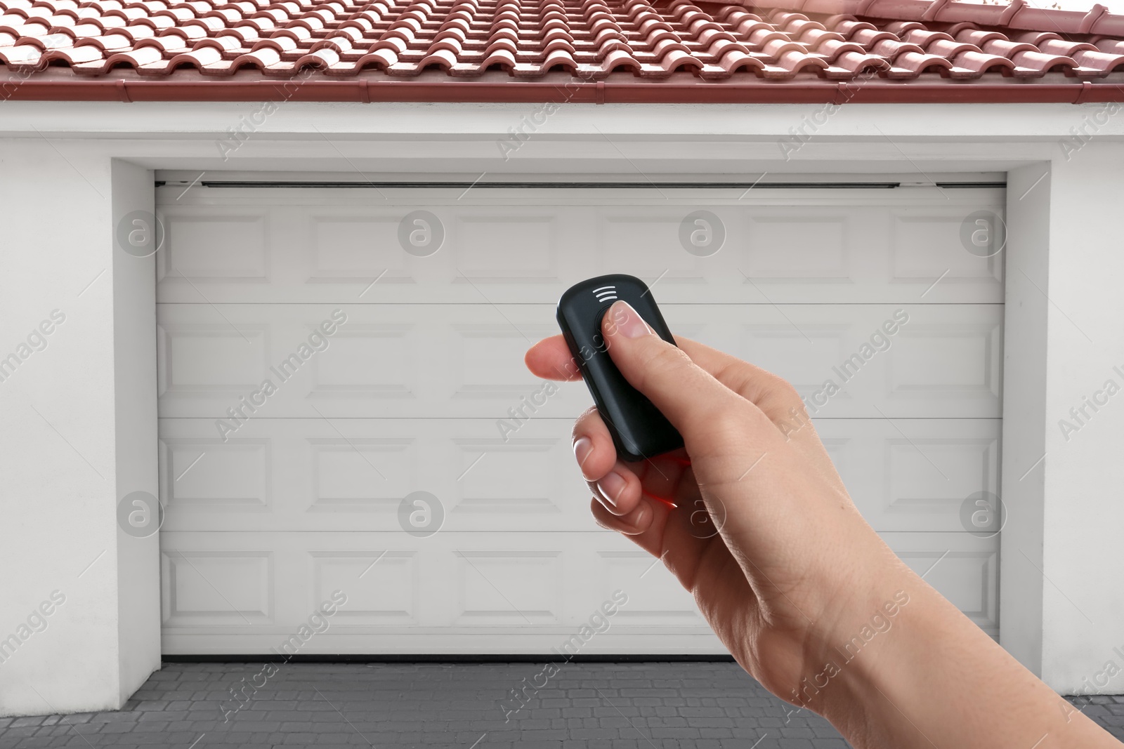 Woman using remote to control garage door outdoors, closeup Image of Woman using remote to control garage door outdoors, closeup