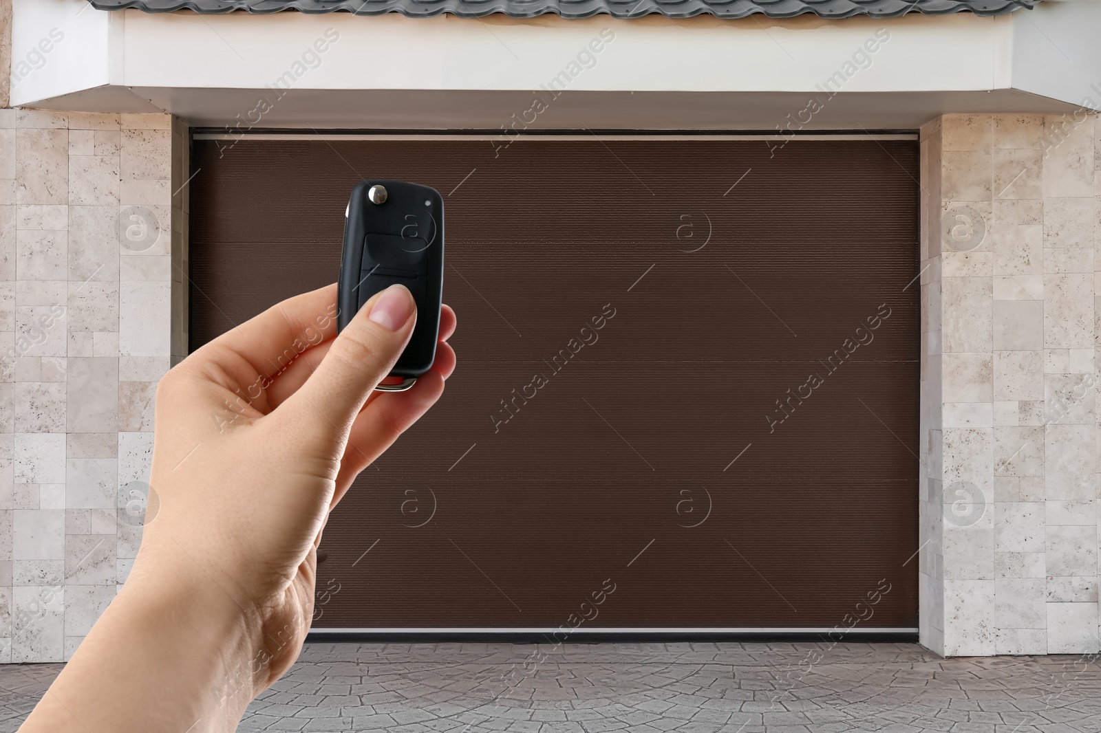 Woman using remote to control garage door outdoors, closeup Image of Woman using remote to control garage door outdoors, closeup
