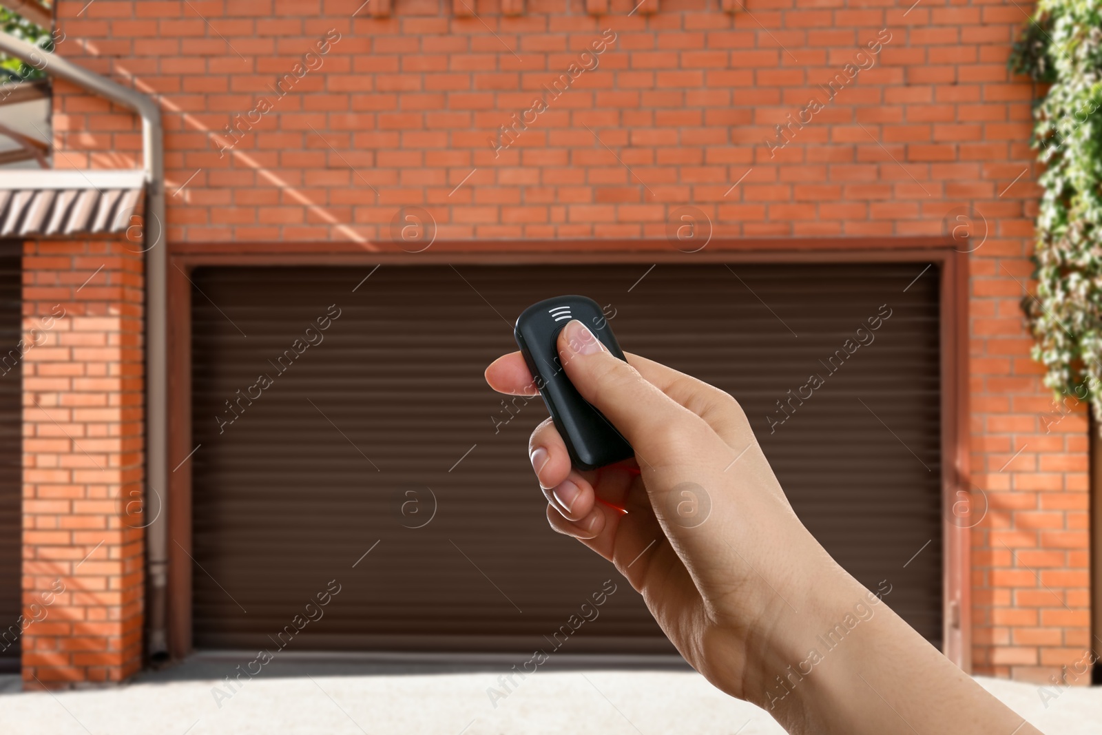 Woman using remote to control garage door outdoors, closeup Image of Woman using remote to control garage door outdoors, closeup