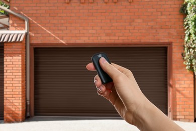 Image of Woman using remote to control garage door outdoors, closeup