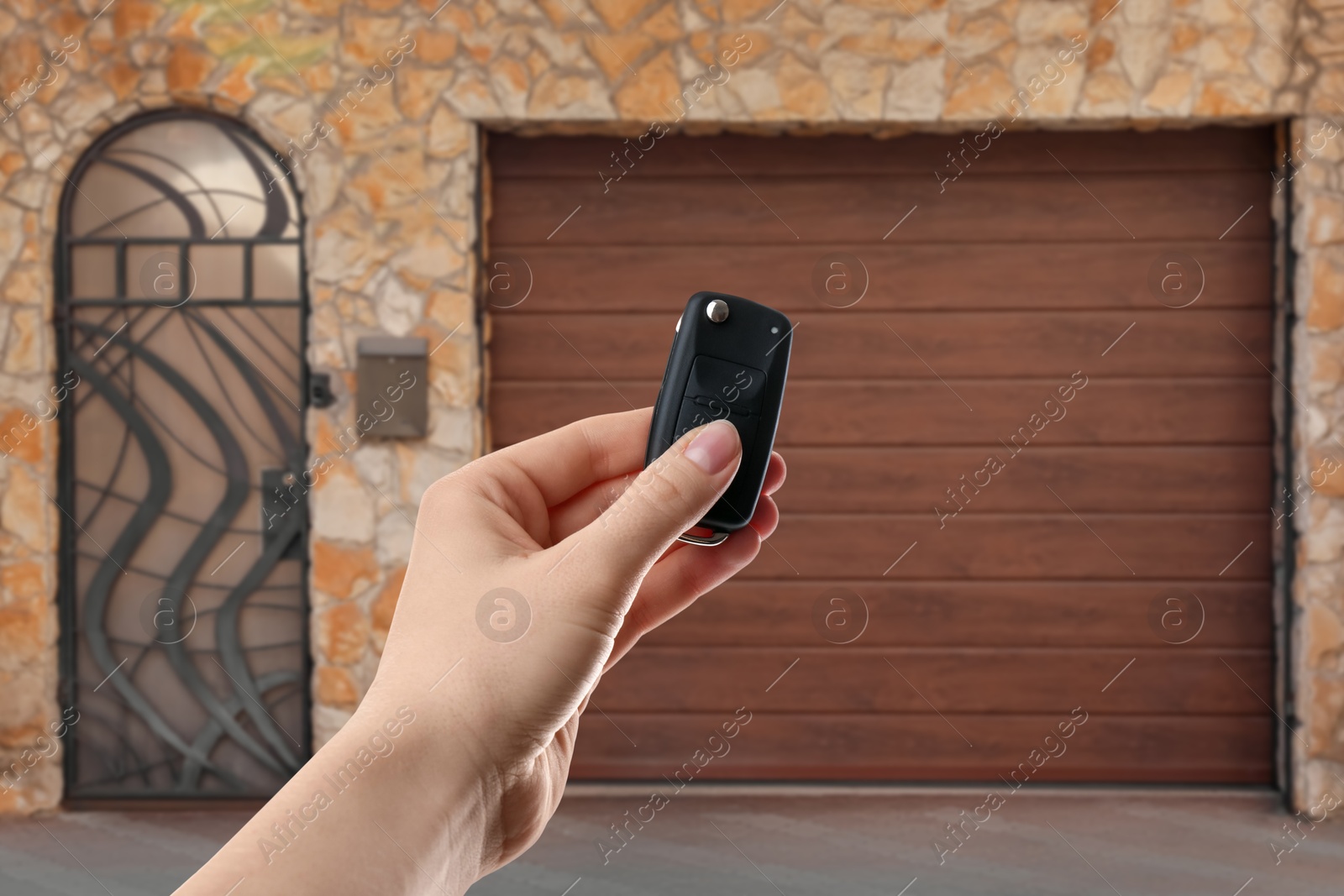 Woman using remote to control electric gate outdoors, closeup Image of Woman using remote to control electric gate outdoors, closeup