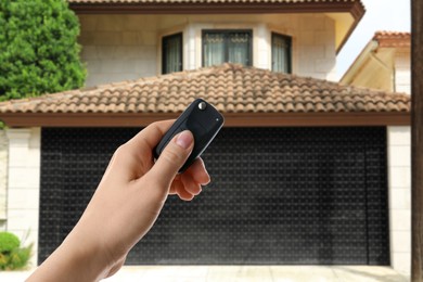 Image of Woman using remote to control garage door outdoors, closeup