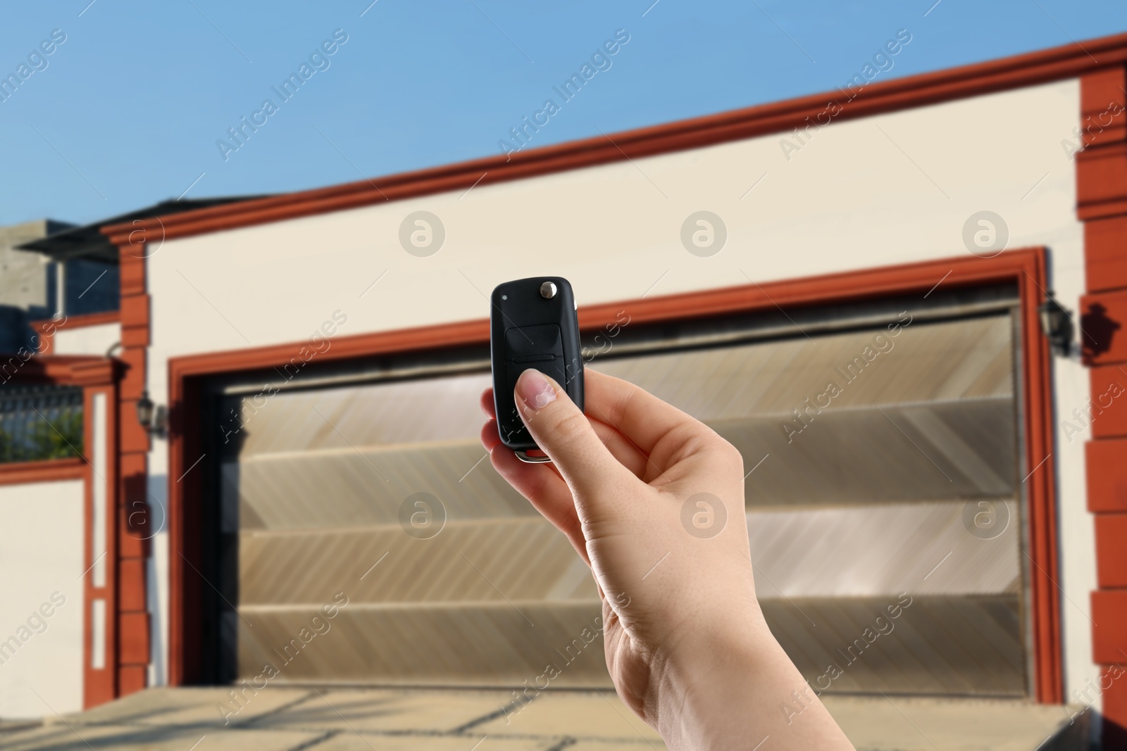 Woman using remote to control garage door outdoors, closeup Image of Woman using remote to control garage door outdoors, closeup