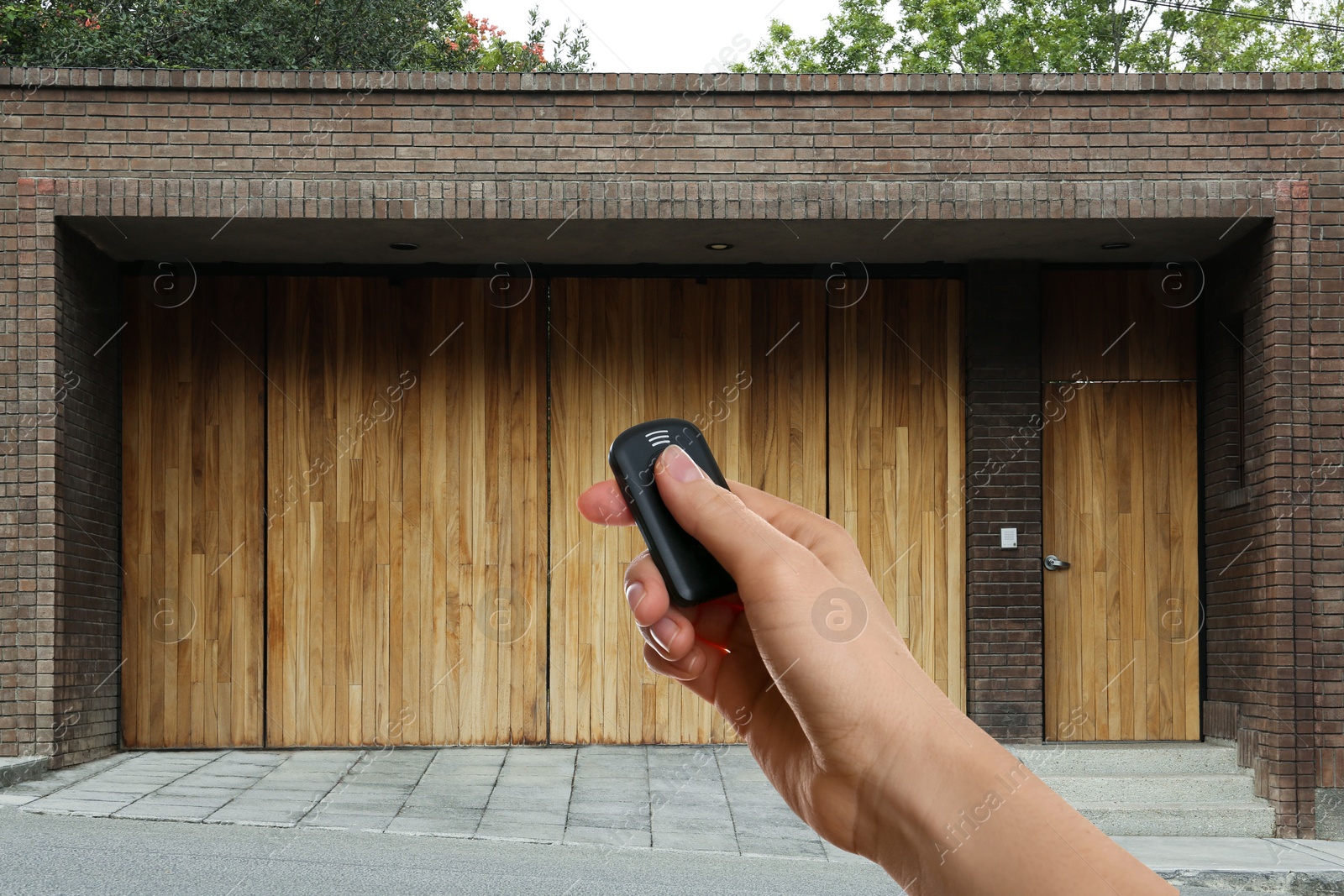 Woman using remote to control electric gate outdoors, closeup Image of Woman using remote to control electric gate outdoors, closeup