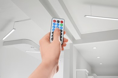 Image of Woman using remote to control lighting in room, closeup