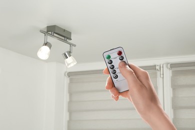 Image of Woman using remote to control lighting in room, closeup