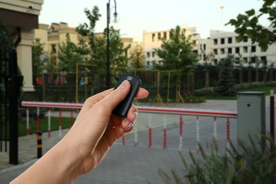 Image of Woman using remote to control boom barrier outdoors, closeup