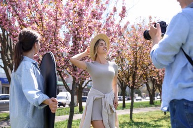 Photo of Professional photographers with reflector and camera near model during shooting outdoors on sunny day