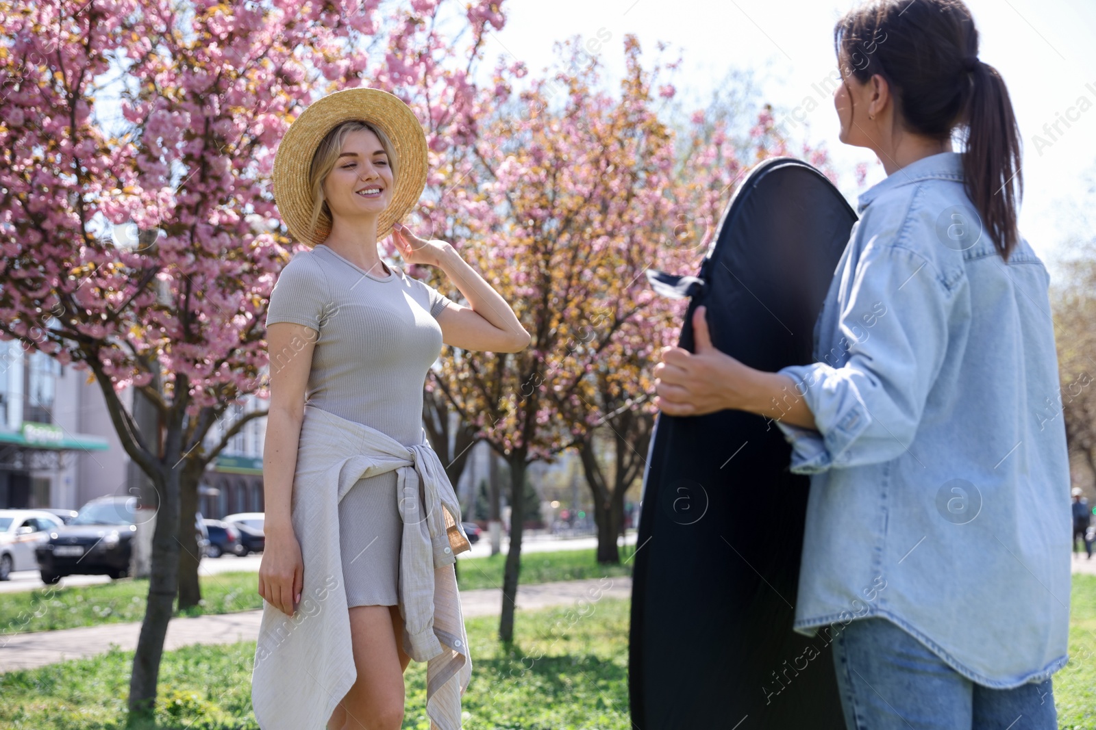 Professional photographer with reflector near model during shooting outdoors on sunny day Photo of Professional photographer with reflector near model during shooting outdoors on sunny day