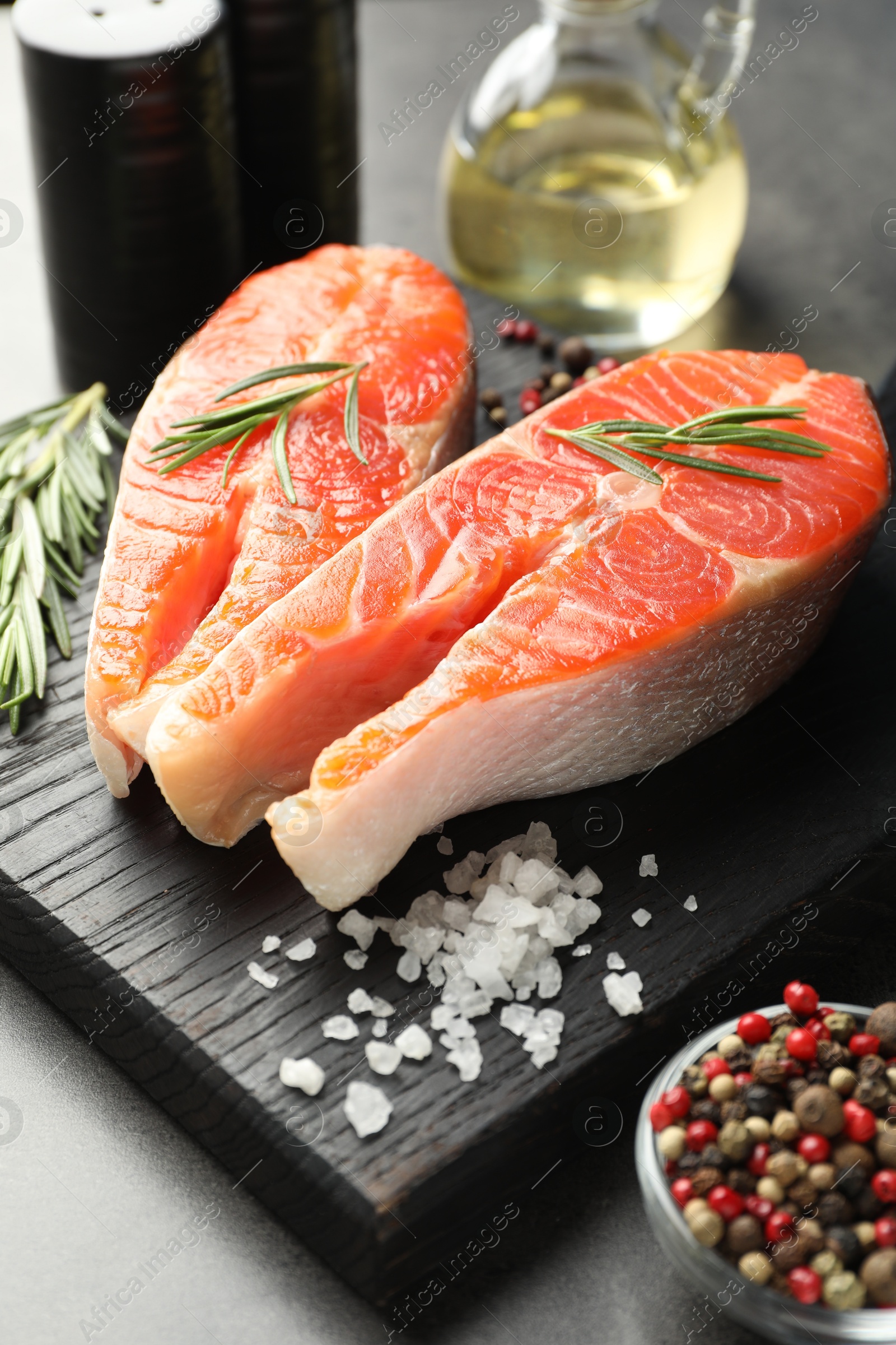 Seafood. Raw salmon steaks, rosemary and spices on grey table, closeup Photo of Seafood. Raw salmon steaks, rosemary and spices on grey table, closeup