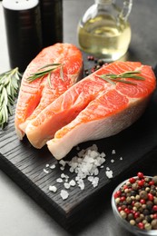 Photo of Seafood. Raw salmon steaks, rosemary and spices on grey table, closeup