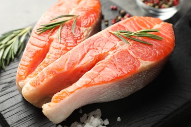 Photo of Seafood. Raw salmon steaks, rosemary and spices on grey table, closeup