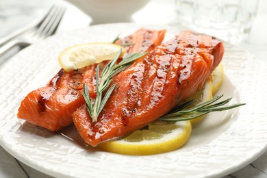 Photo of Seafood. Tasty grilled salmon served with rosemary and lemon on white table, closeup
