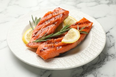 Photo of Seafood. Tasty grilled salmon served with rosemary and lemon on white marble table, closeup