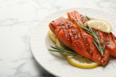 Photo of Seafood. Tasty grilled salmon served with rosemary and lemon on white marble table, closeup. Space for text
