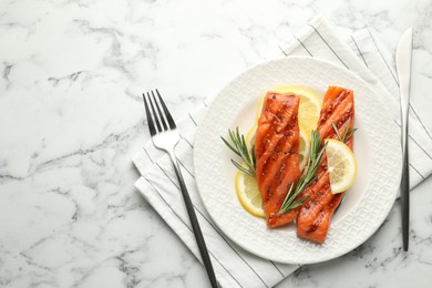 Photo of Seafood. Tasty grilled salmon served with cutlery, rosemary and lemon on white marble table, flat lay. Space for text