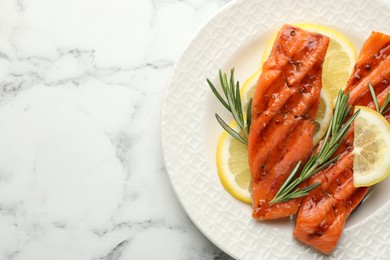 Photo of Seafood. Tasty grilled salmon served with rosemary and lemon on white marble table, top view. Space for text