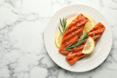 Photo of Seafood. Tasty grilled salmon served with rosemary and lemon on white marble table, top view. Space for text
