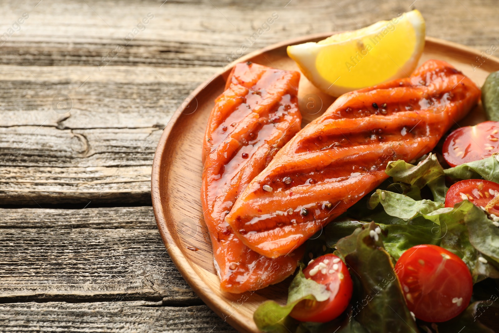 Seafood. Tasty grilled salmon served with salad and lemon on wooden table, closeup. Space for text Photo of Seafood. Tasty grilled salmon served with salad and lemon on wooden table, closeup. Space for text